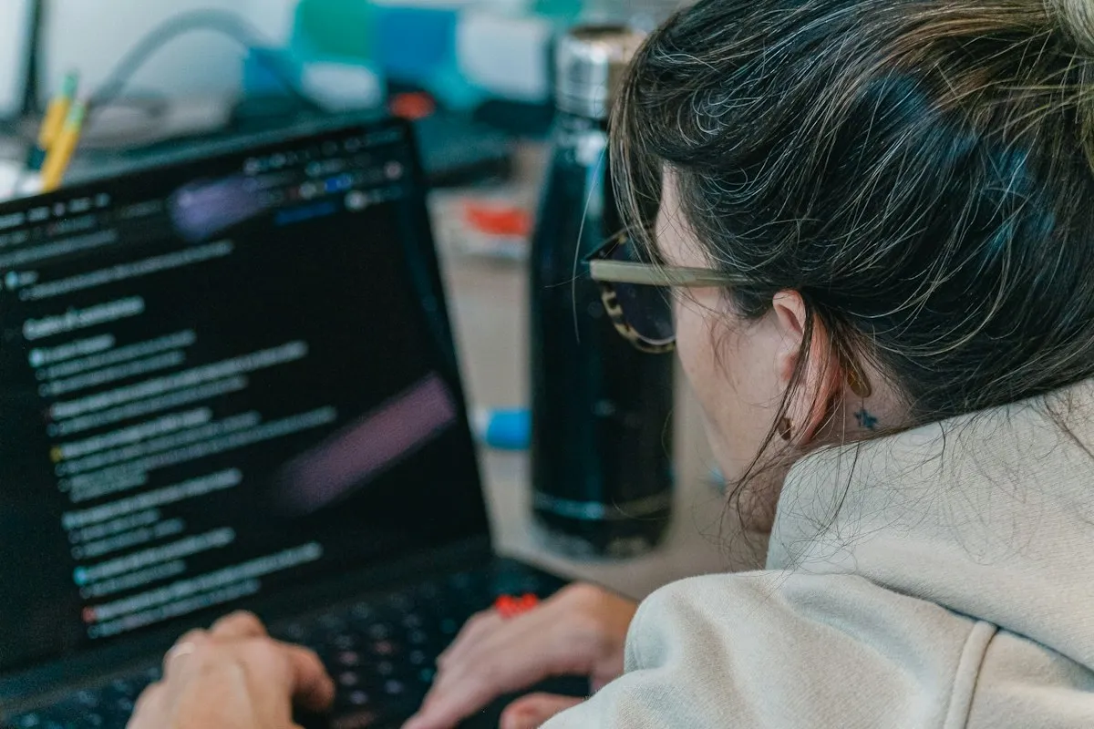 A software engineer working at a laptop displaying lines of code in a modern workspace