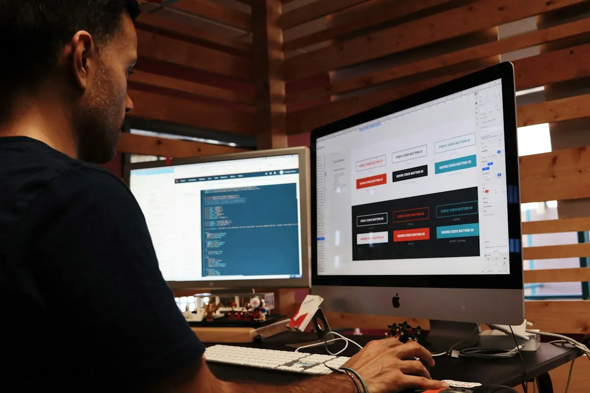 Professional working at computer monitors with code on screen